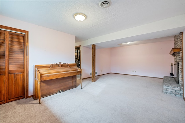 interior space featuring a fireplace, light colored carpet, and a textured ceiling