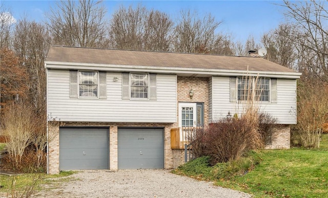 split foyer home with brick siding, driveway, and an attached garage