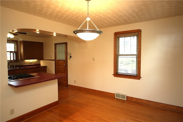 unfurnished dining area featuring wood-type flooring, ceiling fan, and sink