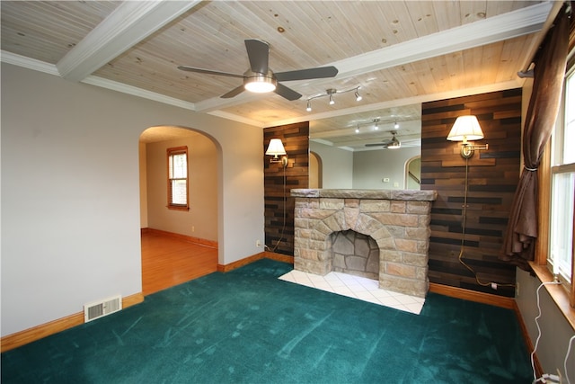 unfurnished living room featuring wooden ceiling, crown molding, wooden walls, a fireplace, and dark carpet