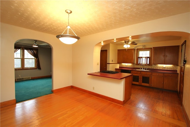 kitchen featuring sink, black gas cooktop, dark hardwood / wood-style flooring, kitchen peninsula, and decorative light fixtures