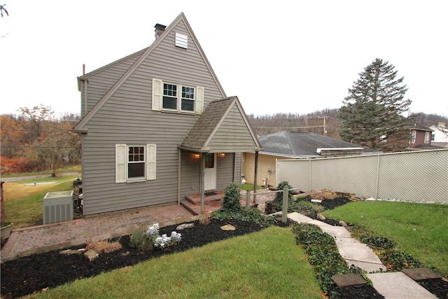 rear view of property featuring a yard and cooling unit