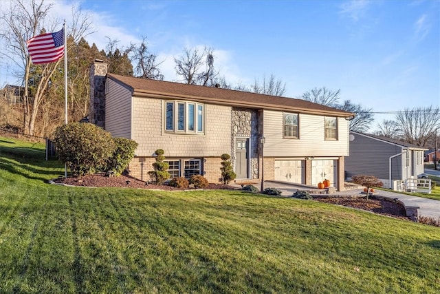 raised ranch featuring a garage and a front lawn