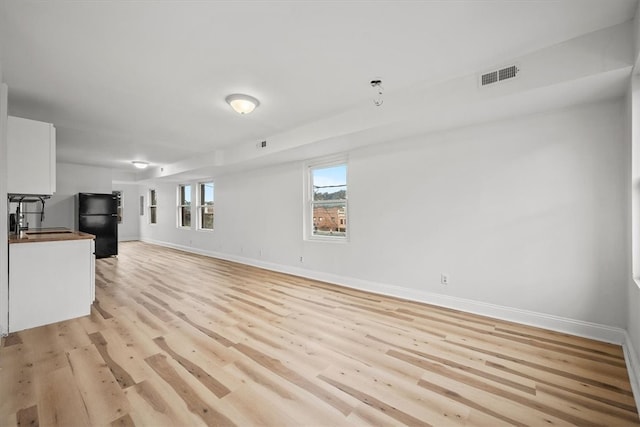 unfurnished living room with light hardwood / wood-style floors and sink