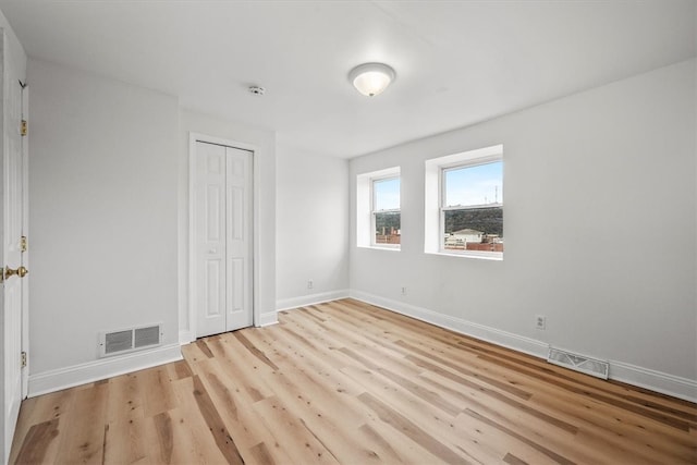 unfurnished bedroom with light wood-type flooring and a closet