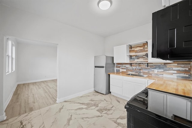 kitchen featuring white cabinets, stainless steel fridge, decorative backsplash, and sink