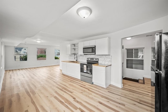 kitchen with backsplash, wooden counters, sink, white cabinetry, and stainless steel appliances