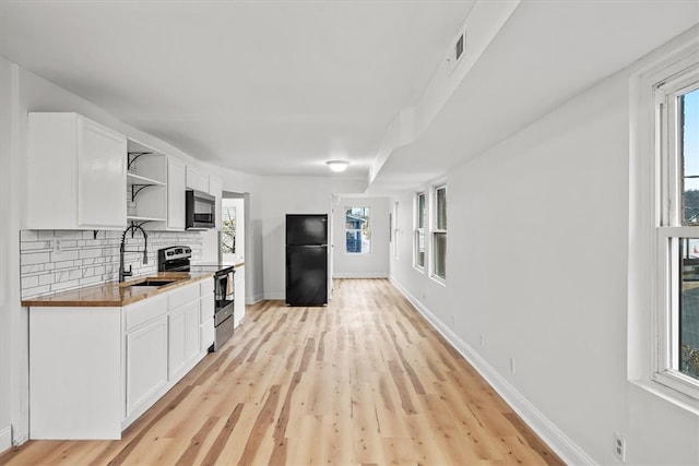 kitchen featuring white cabinets, sink, decorative backsplash, light hardwood / wood-style floors, and stainless steel appliances