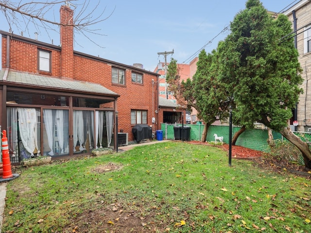 rear view of house featuring central air condition unit and a lawn