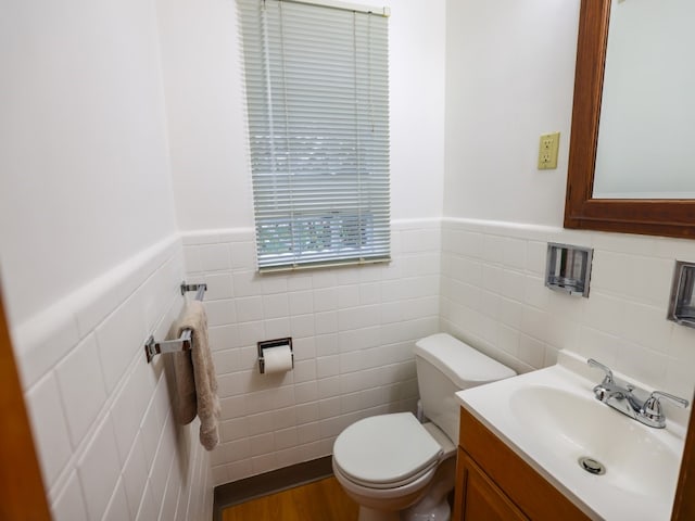 bathroom with hardwood / wood-style flooring, vanity, tile walls, and toilet