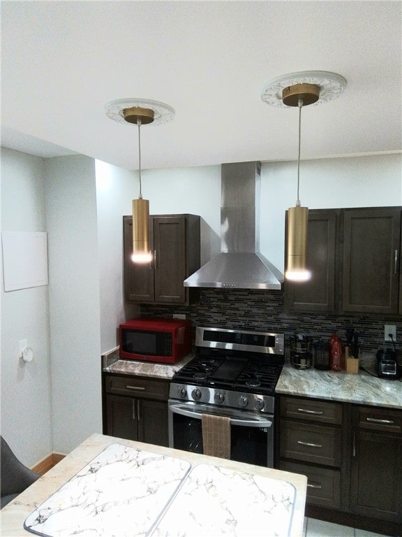 kitchen with pendant lighting, stainless steel gas range, wall chimney exhaust hood, decorative backsplash, and dark brown cabinetry