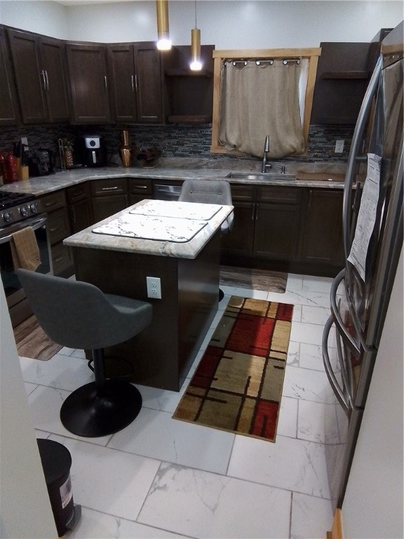 kitchen featuring black refrigerator, decorative light fixtures, tasteful backsplash, and sink