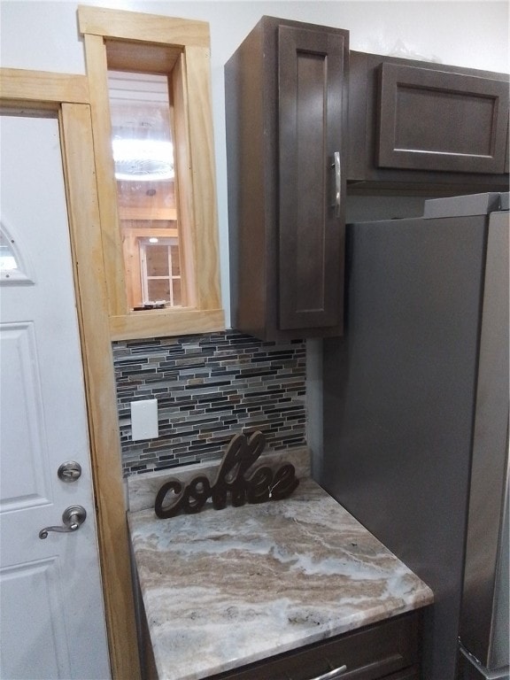 kitchen with dark brown cabinets, tasteful backsplash, and stainless steel refrigerator