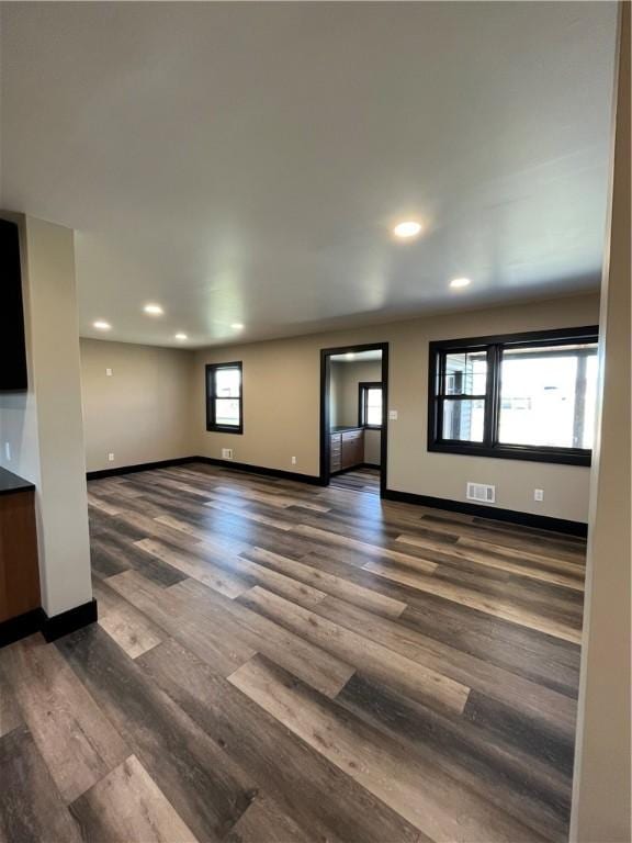 unfurnished living room featuring dark hardwood / wood-style flooring and a healthy amount of sunlight