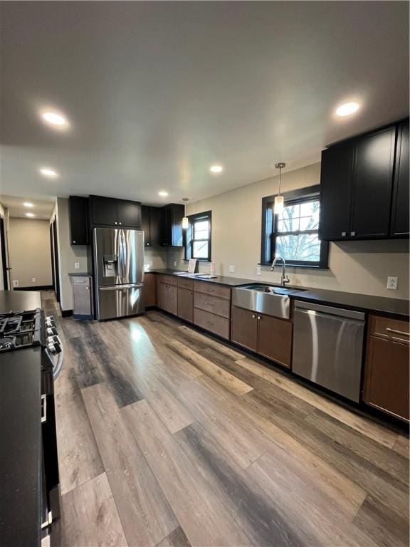 kitchen with pendant lighting, sink, light hardwood / wood-style flooring, and appliances with stainless steel finishes