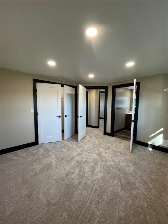 unfurnished bedroom featuring ensuite bathroom and light colored carpet