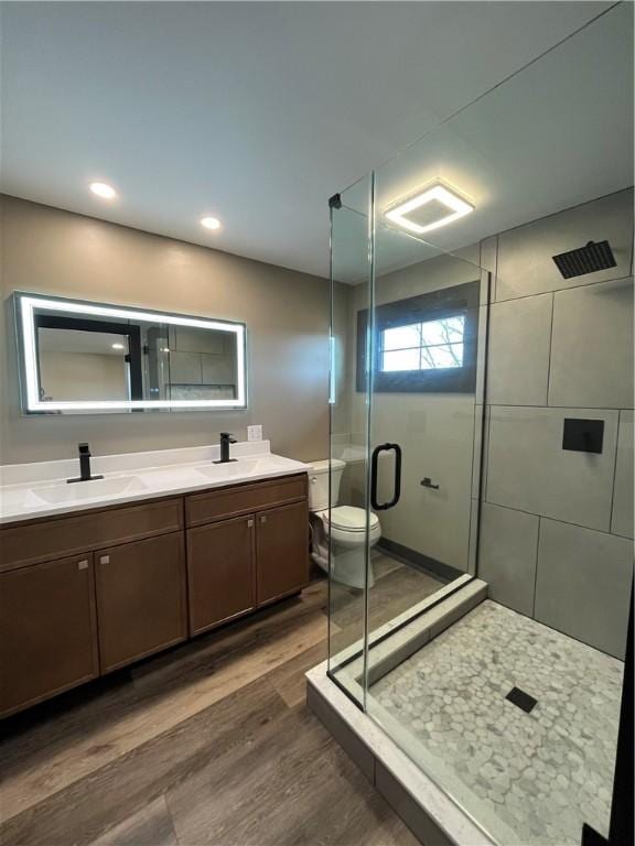 bathroom with hardwood / wood-style floors, vanity, toilet, and an enclosed shower