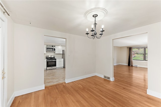 unfurnished dining area with a chandelier and light hardwood / wood-style floors