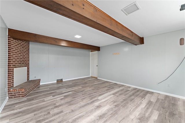 basement with a brick fireplace and light hardwood / wood-style flooring