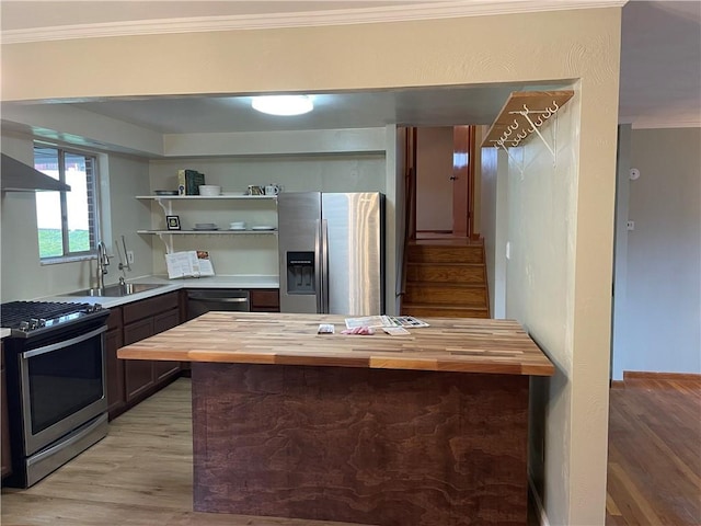 kitchen featuring sink, stainless steel appliances, butcher block countertops, crown molding, and light hardwood / wood-style floors