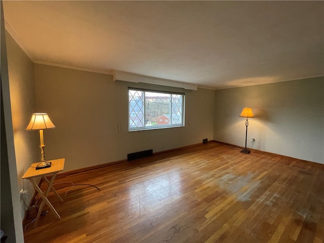 empty room featuring wood-type flooring and ornamental molding