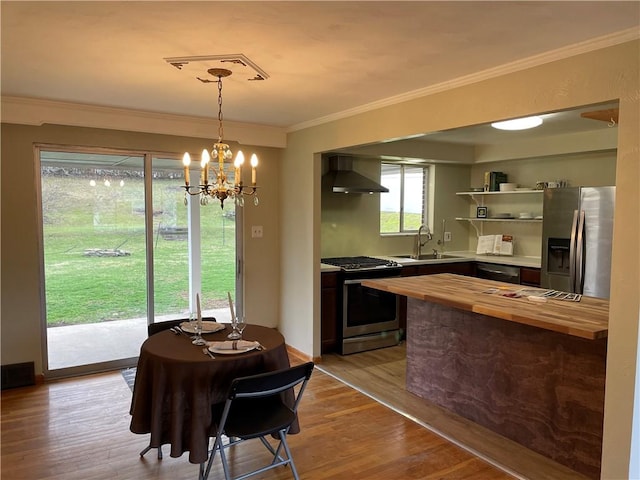 dining space featuring light wood-type flooring, crown molding, a notable chandelier, and sink