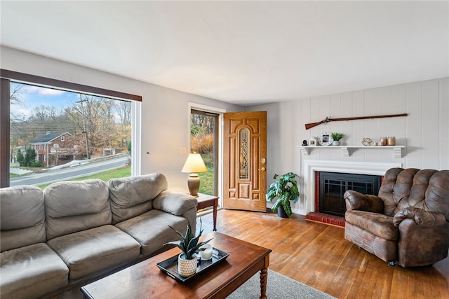 living room with a brick fireplace and hardwood / wood-style flooring