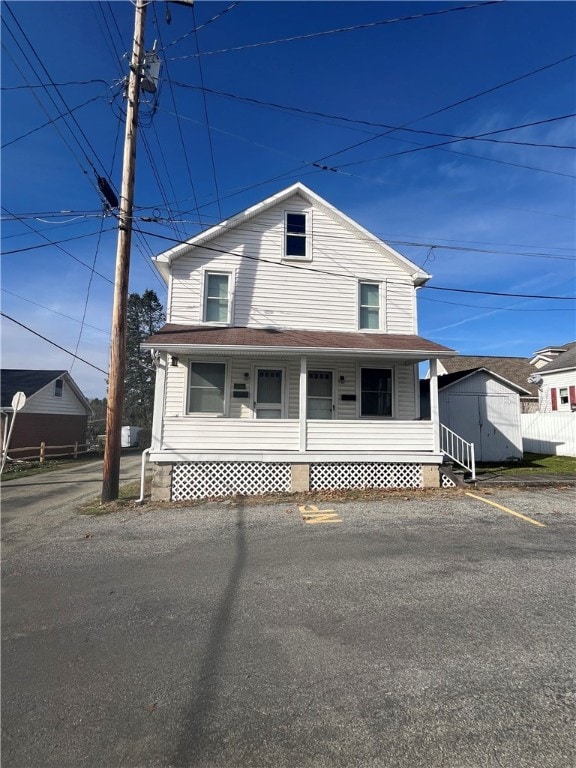 view of front of home featuring covered porch and a shed