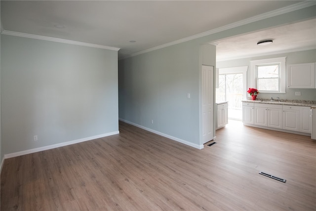 unfurnished living room with light hardwood / wood-style floors, sink, and crown molding