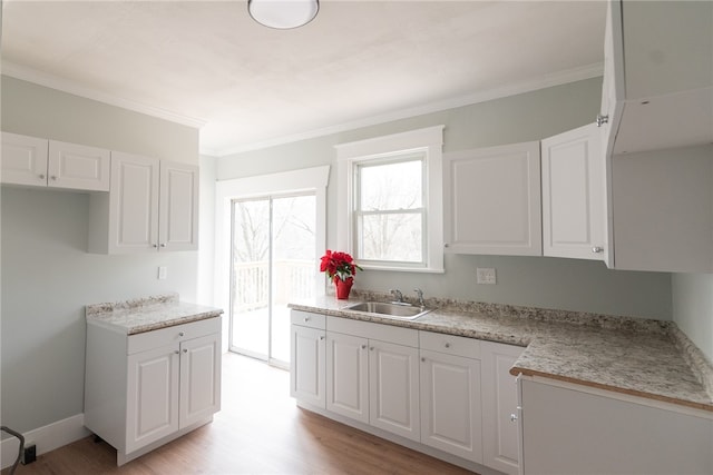 kitchen with white cabinetry, sink, ornamental molding, and light hardwood / wood-style flooring