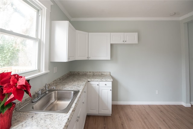 kitchen with crown molding, sink, white cabinets, and light hardwood / wood-style flooring