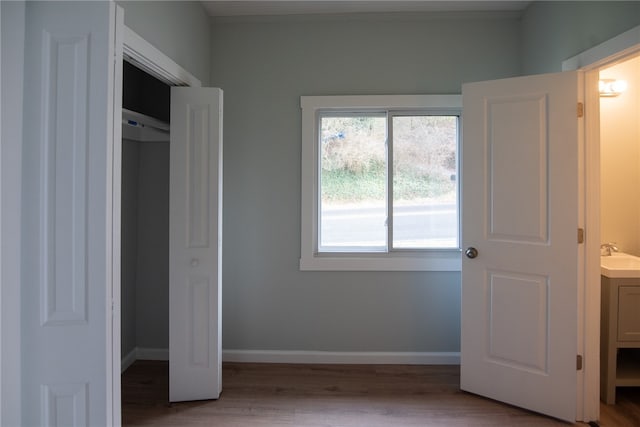 unfurnished bedroom with hardwood / wood-style flooring, sink, and a closet