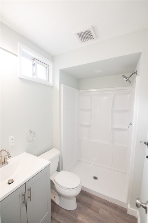 bathroom featuring a shower, toilet, vanity, and hardwood / wood-style flooring