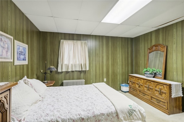 carpeted bedroom featuring radiator heating unit, a paneled ceiling, and wooden walls