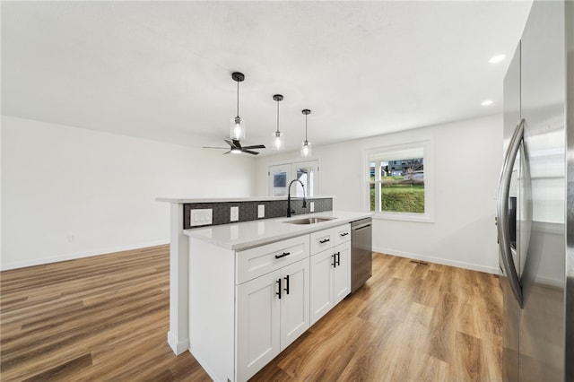 kitchen featuring sink, light hardwood / wood-style flooring, an island with sink, white cabinets, and appliances with stainless steel finishes