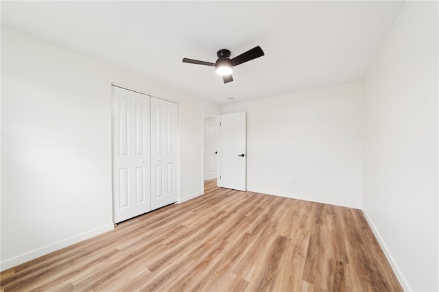 unfurnished bedroom with ceiling fan, light wood-type flooring, and a closet