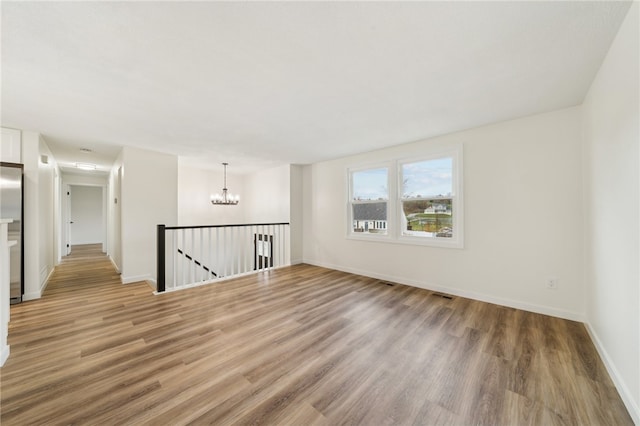 unfurnished room featuring a chandelier and hardwood / wood-style flooring