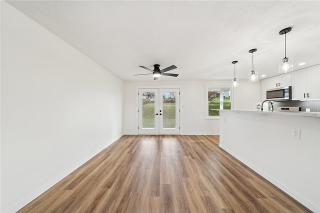 unfurnished living room featuring ceiling fan, light hardwood / wood-style floors, sink, and french doors