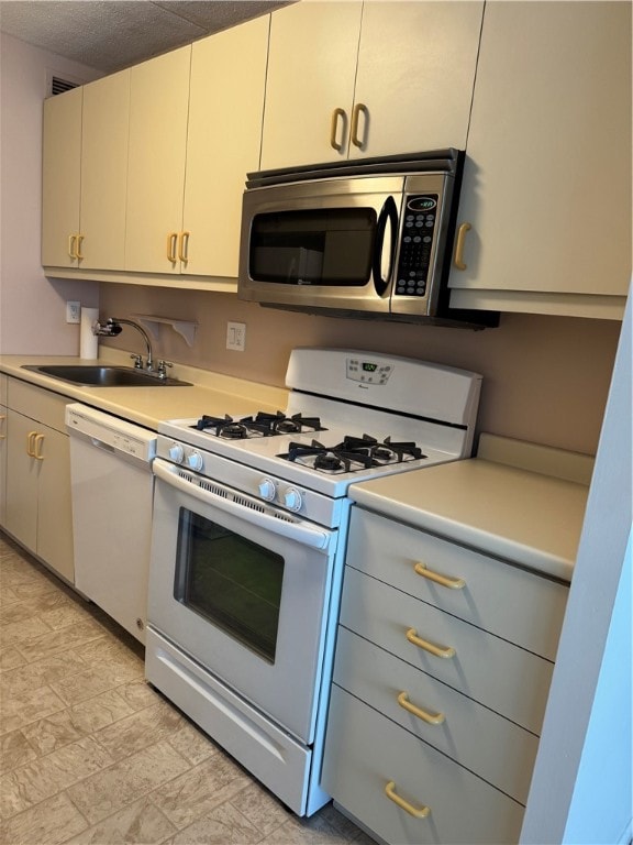 kitchen with a textured ceiling, sink, and white appliances