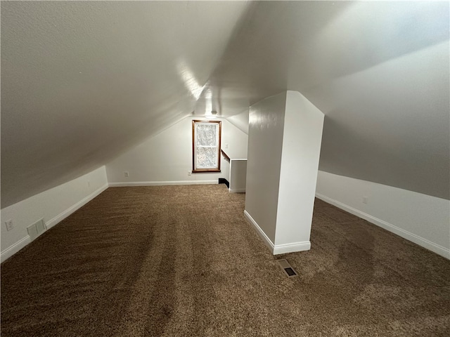 bonus room with dark colored carpet and vaulted ceiling