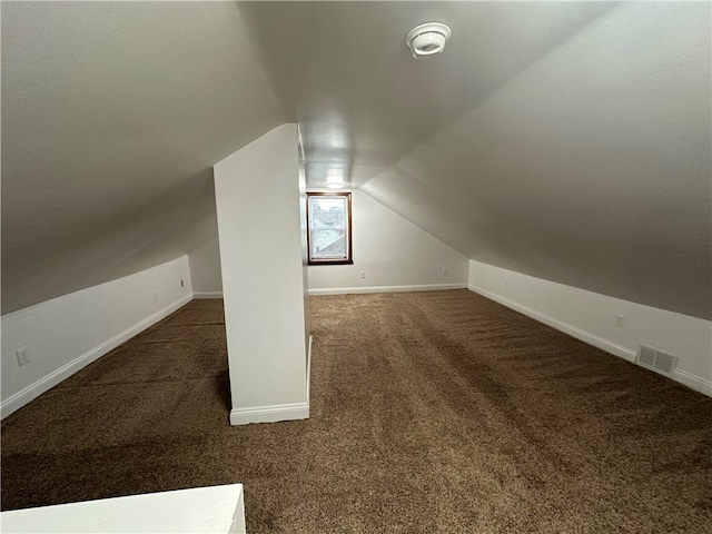 bonus room with vaulted ceiling and dark colored carpet