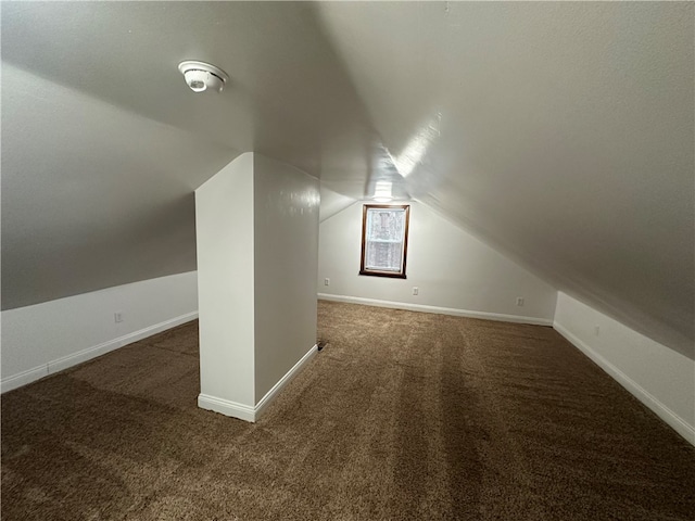 bonus room featuring vaulted ceiling and dark colored carpet