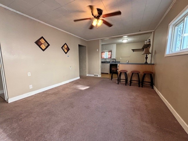 interior space featuring carpet floors, ceiling fan, and crown molding