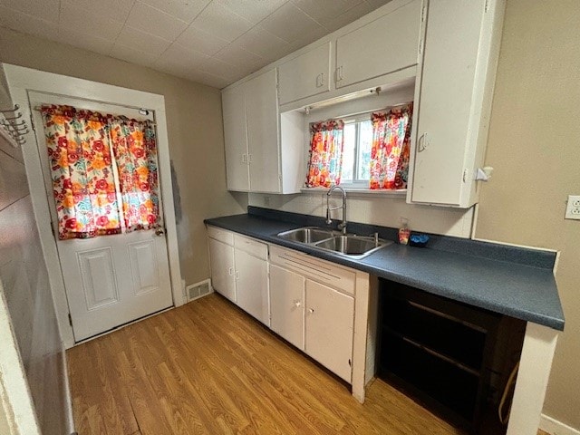 kitchen featuring white cabinets, light hardwood / wood-style floors, and sink