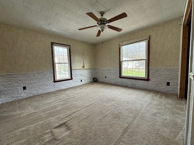 empty room featuring ceiling fan, light colored carpet, and a healthy amount of sunlight