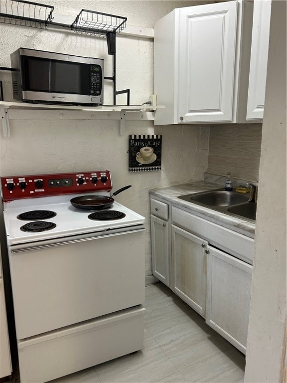 kitchen featuring white cabinets, white electric range oven, and sink