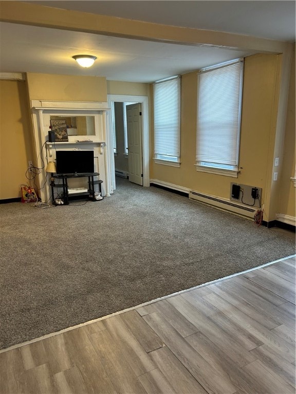 unfurnished living room featuring baseboard heating and wood-type flooring