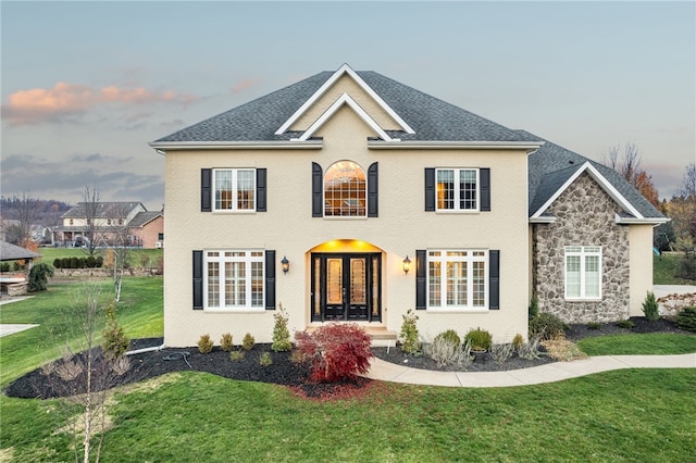 view of front of property with french doors and a yard