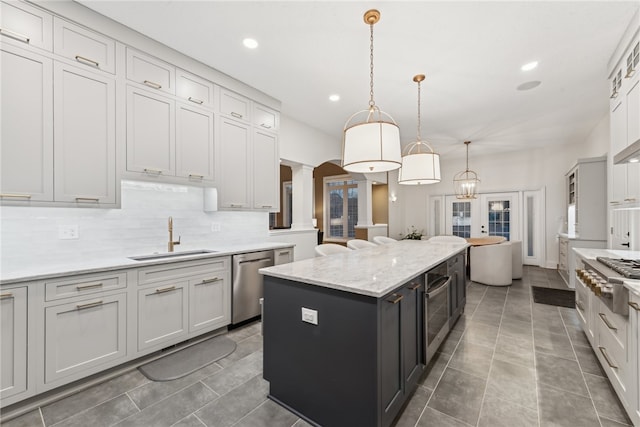 kitchen with pendant lighting, french doors, sink, a kitchen island, and stainless steel appliances