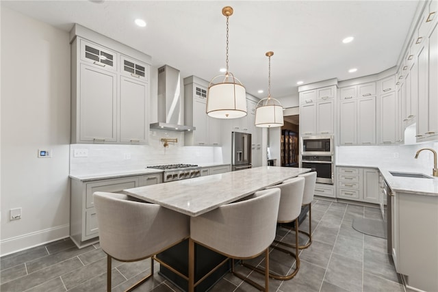 kitchen featuring a center island, sink, wall chimney exhaust hood, stainless steel appliances, and tasteful backsplash